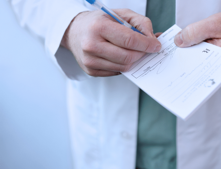 Lekarz w białym kitlu podpisujący dokument medyczny – wystawianie recepty lub zwolnienia lekarskiego