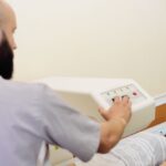 Badanie densytometryczne u młodej kobiety – technik obsługuje aparat do pomiaru gęstości kości.