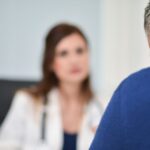 Rozmowa starszego mężczyzny z lekarką podczas konsultacji lekarskiej – widok z perspektywy pacjenta.