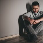 Mężczyzna z objawami depresji siedzący samotnie na podłodze
