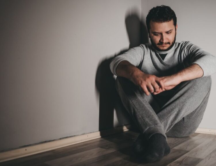 Mężczyzna z objawami depresji siedzący samotnie na podłodze