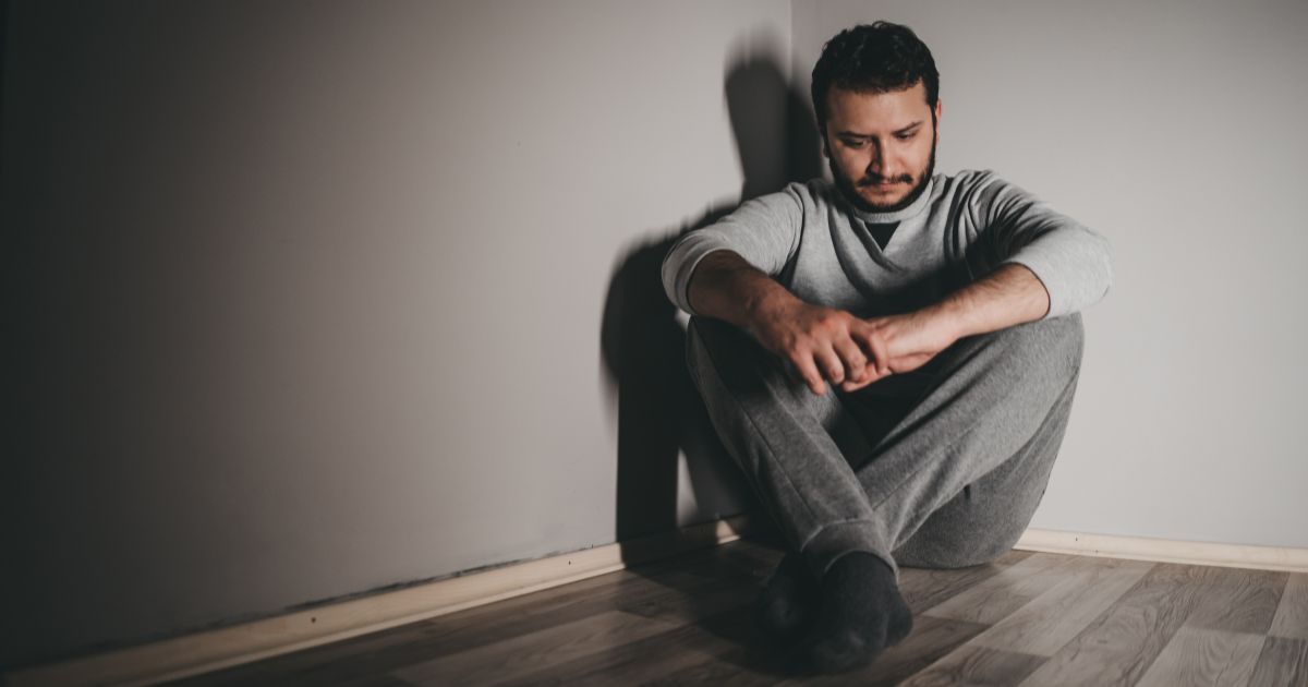 Mężczyzna z objawami depresji siedzący samotnie na podłodze