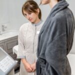 Kobieta w szlafroku podczas analizy składu ciała na nowoczesnym urządzeniu medycznym